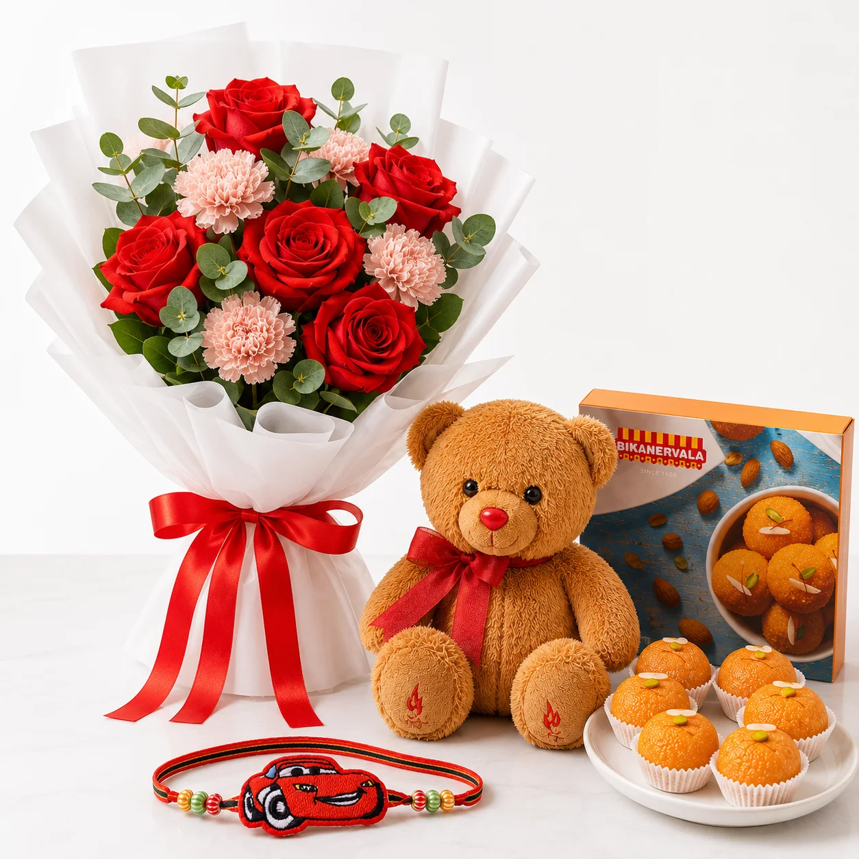 Sweet Red Blossom Rakhi Combo with red roses, pink carnations, teddy, motichur laddoo and Cars theme rakhi